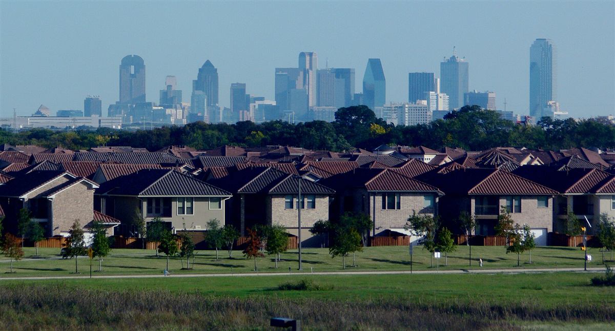 Rows of family homes with a city skyline behind