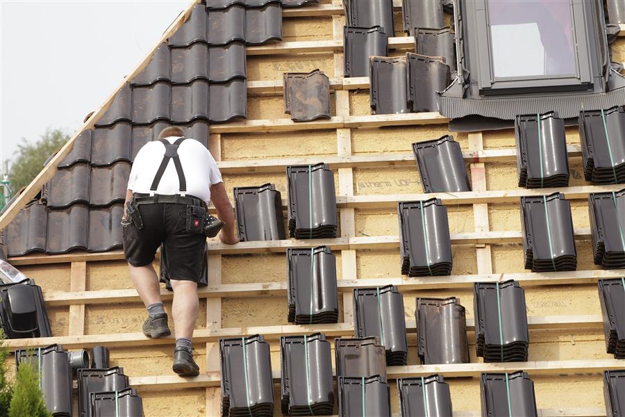 A roofer laying tiles on a new roof